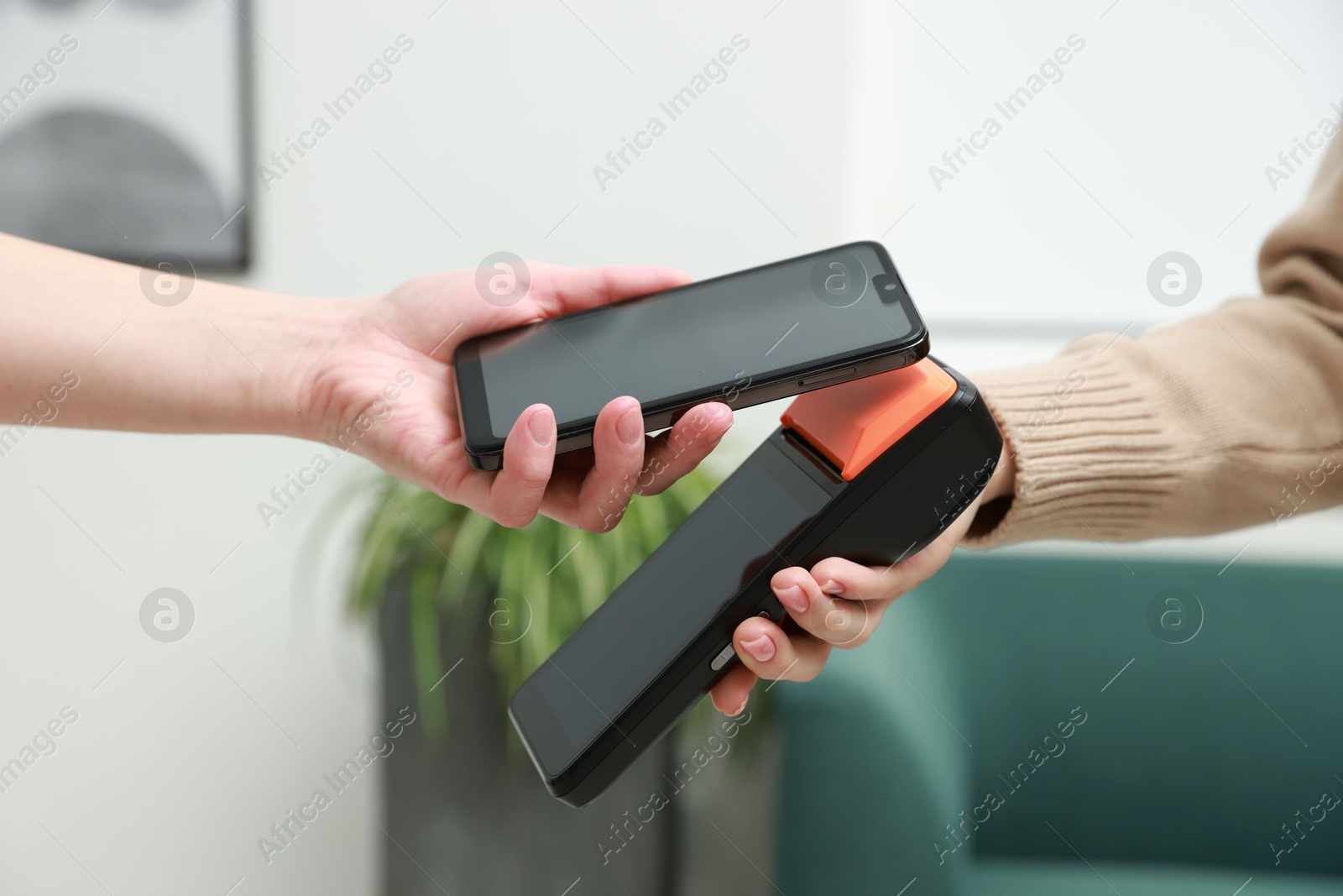 Photo of Woman paying for service with smartphone via terminal indoors, closeup