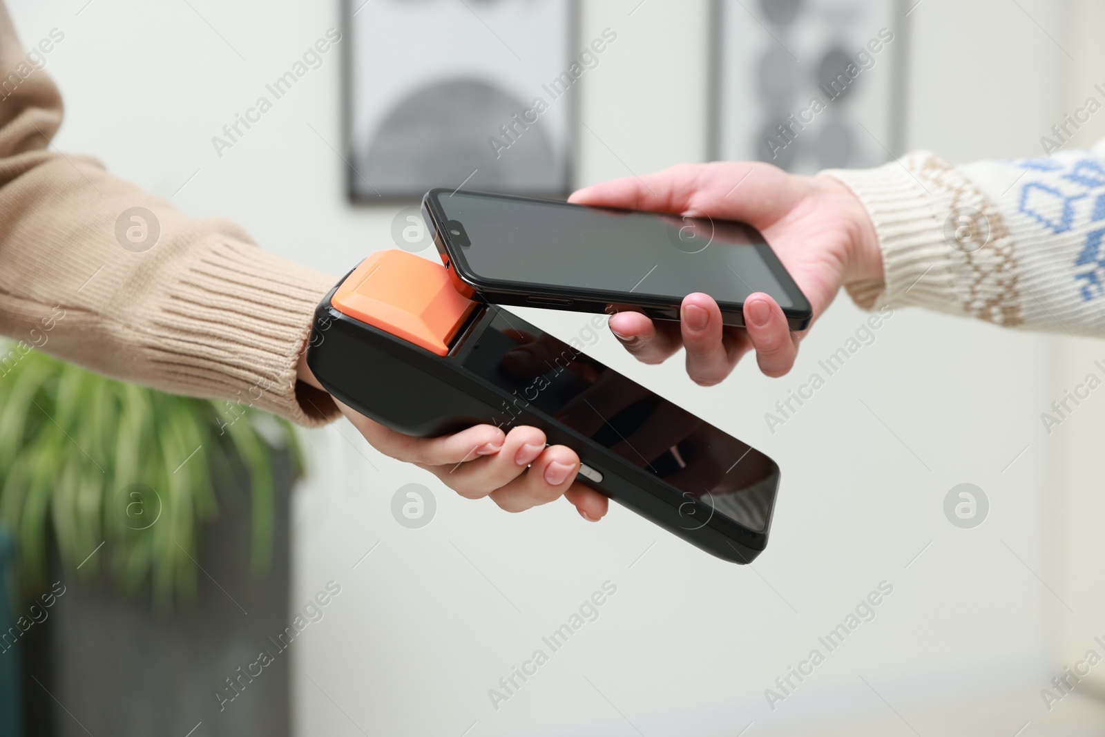 Photo of Woman paying for service with smartphone via terminal indoors, closeup