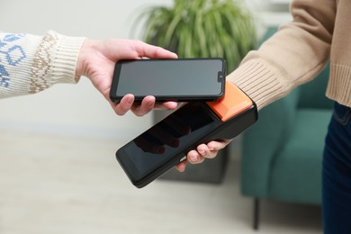 Photo of Woman paying for service with smartphone via terminal indoors, closeup