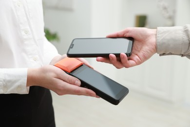 Photo of Woman paying for service with smartphone via terminal indoors, closeup