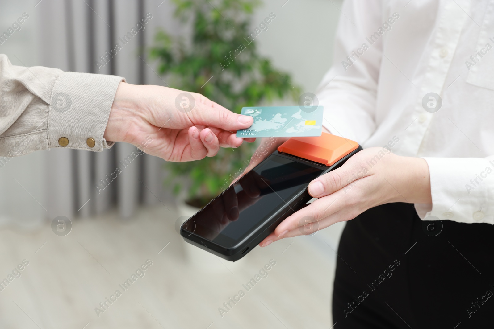 Photo of Woman paying for service with credit card via terminal indoors, closeup