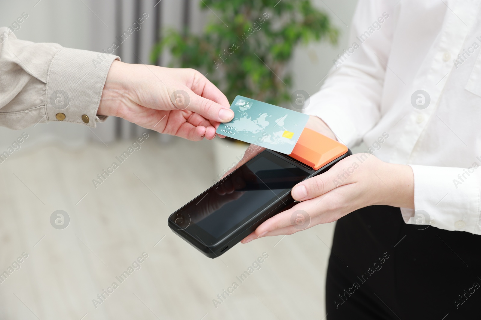 Photo of Woman paying for service with credit card via terminal indoors, closeup