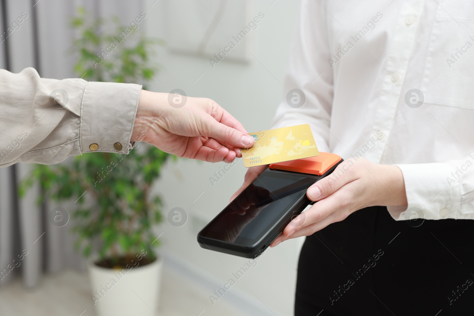 Photo of Woman paying for service with credit card via terminal indoors, closeup