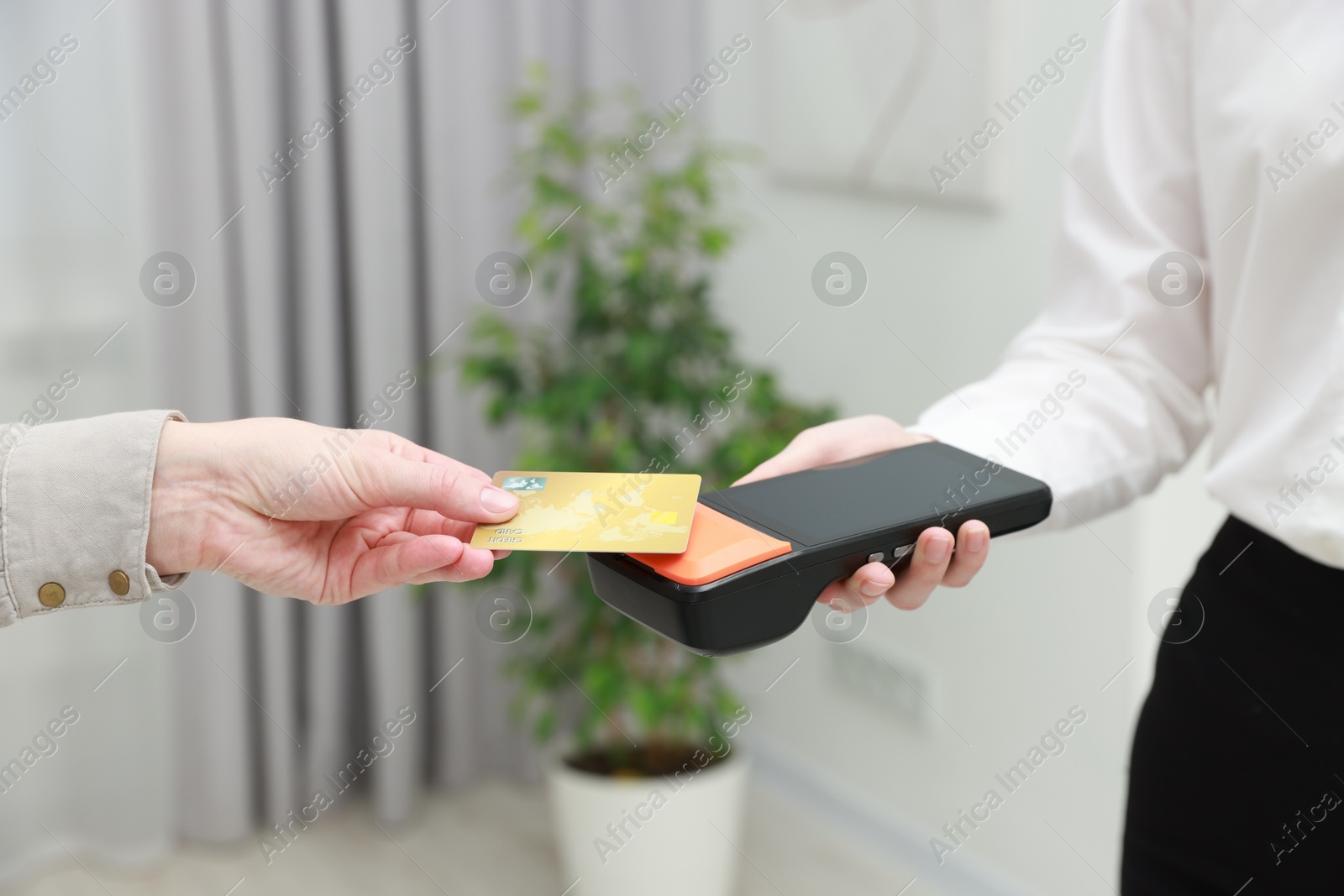 Photo of Woman paying for service with credit card via terminal indoors, closeup