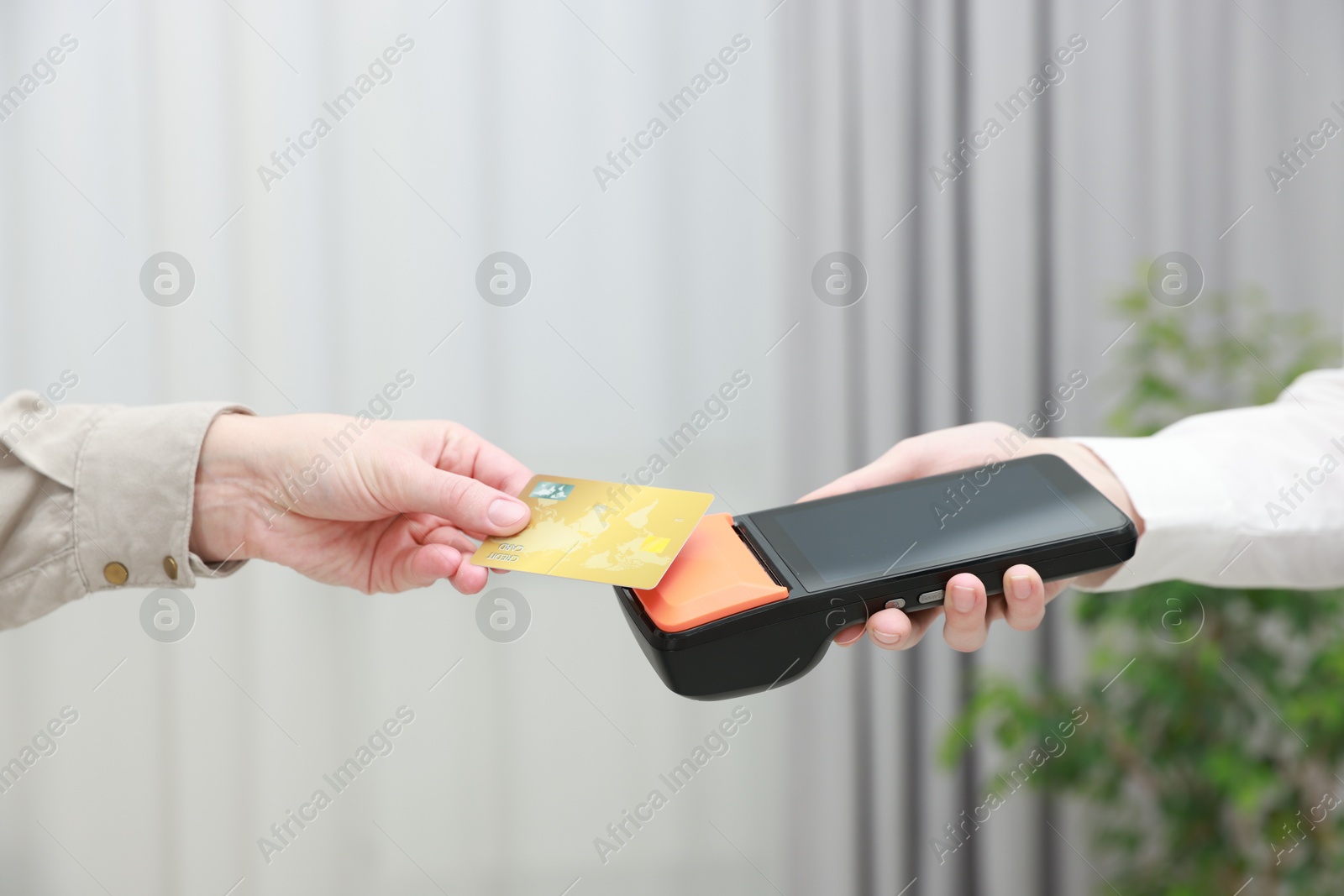 Photo of Woman paying for service with credit card via terminal indoors, closeup