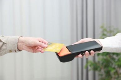 Woman paying for service with credit card via terminal indoors, closeup