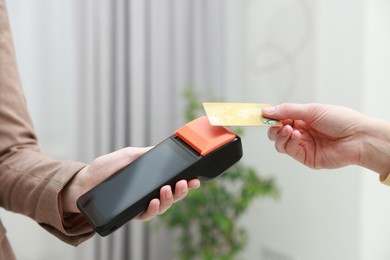 Photo of Woman paying for service with credit card via terminal indoors, closeup