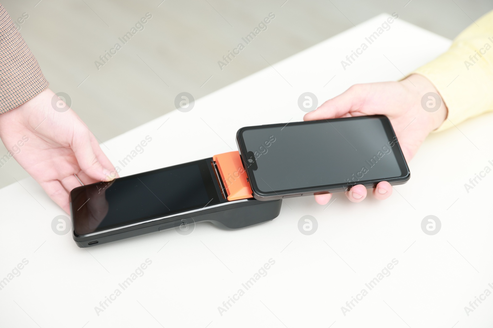 Photo of Woman paying for service with smartphone via terminal at white table indoors, closeup