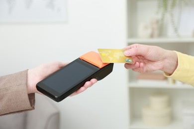 Photo of Woman paying for service with credit card via terminal indoors, closeup