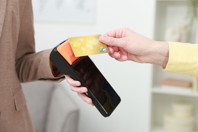 Photo of Woman paying for service with credit card via terminal indoors, closeup