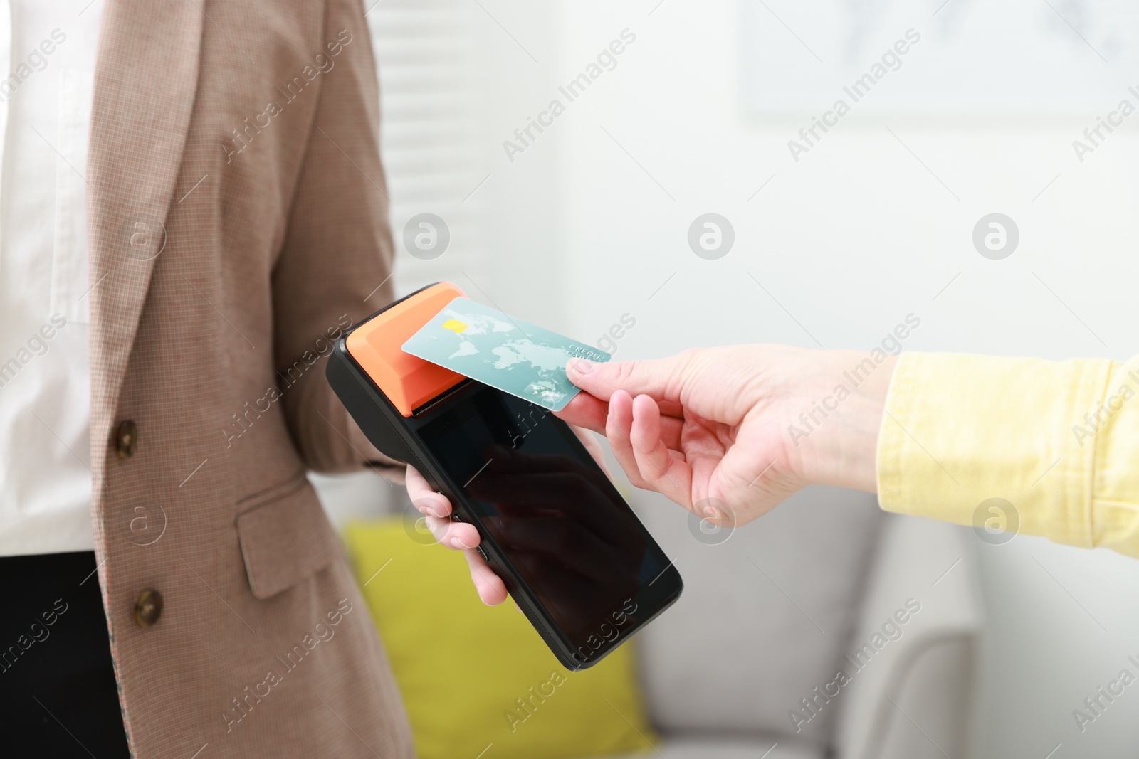 Photo of Woman paying for service with credit card via terminal indoors, closeup