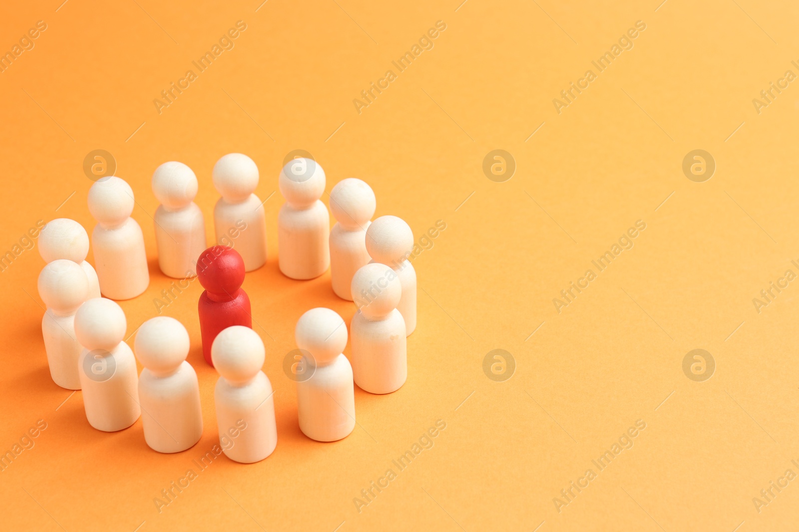 Photo of Competition concept. Red human figure among white ones on orange background, closeup. Space for text