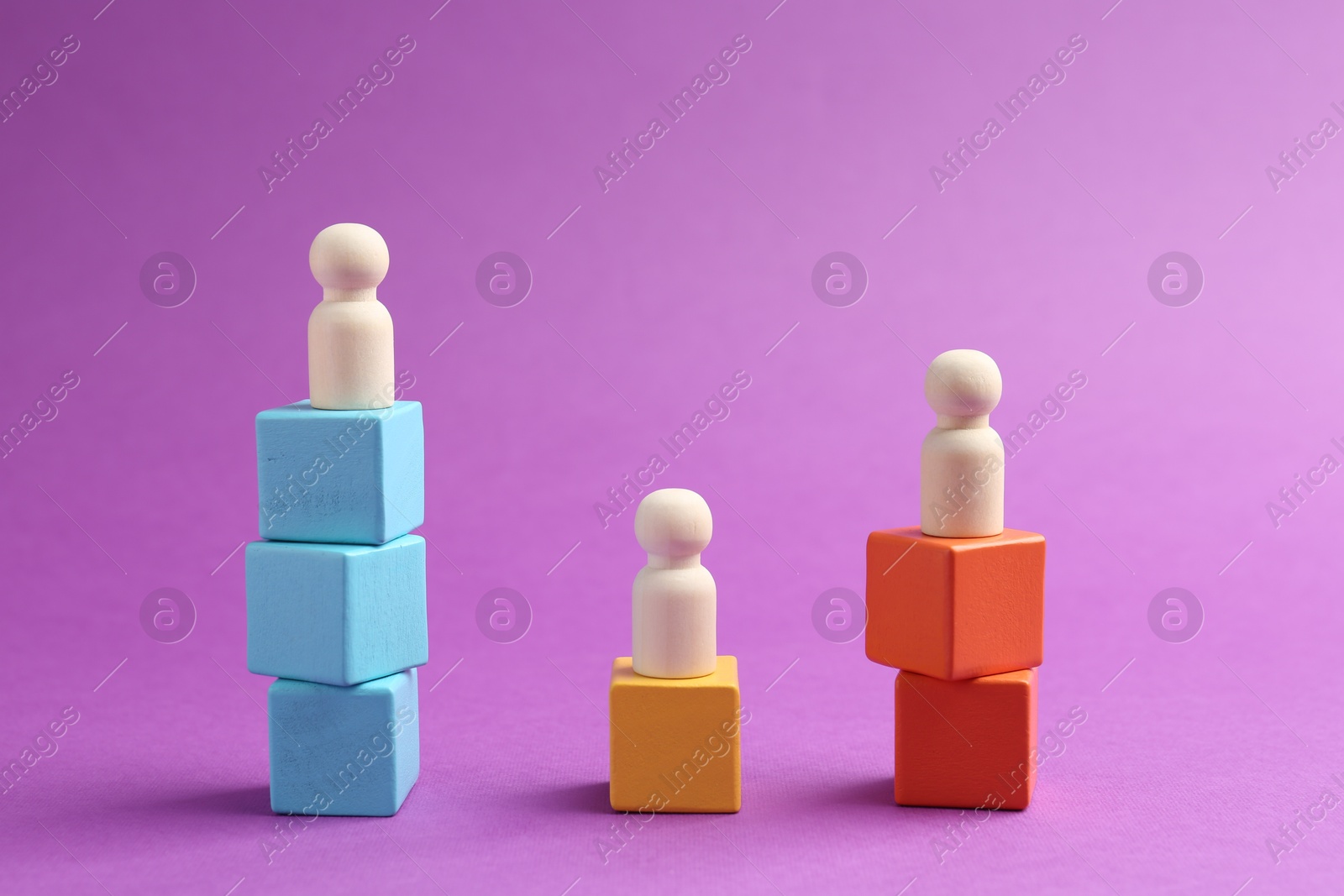 Photo of Human figures on stacked wooden cubes against violet background. Competition concept