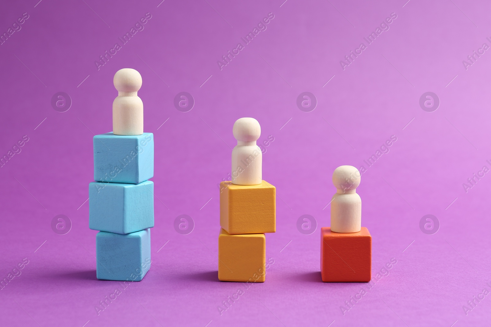 Photo of Human figures on stacked wooden cubes against violet background. Competition concept