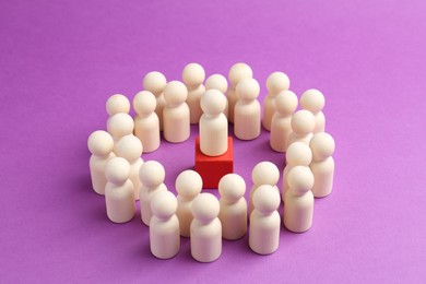 Photo of Human figures around red cube with white figure on violet background, closeup. Competition concept