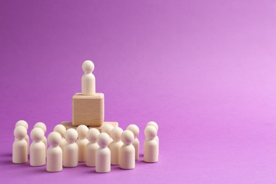 Photo of Human figures near stacked wooden cubes with one figure against violet background, space for text. Competition concept