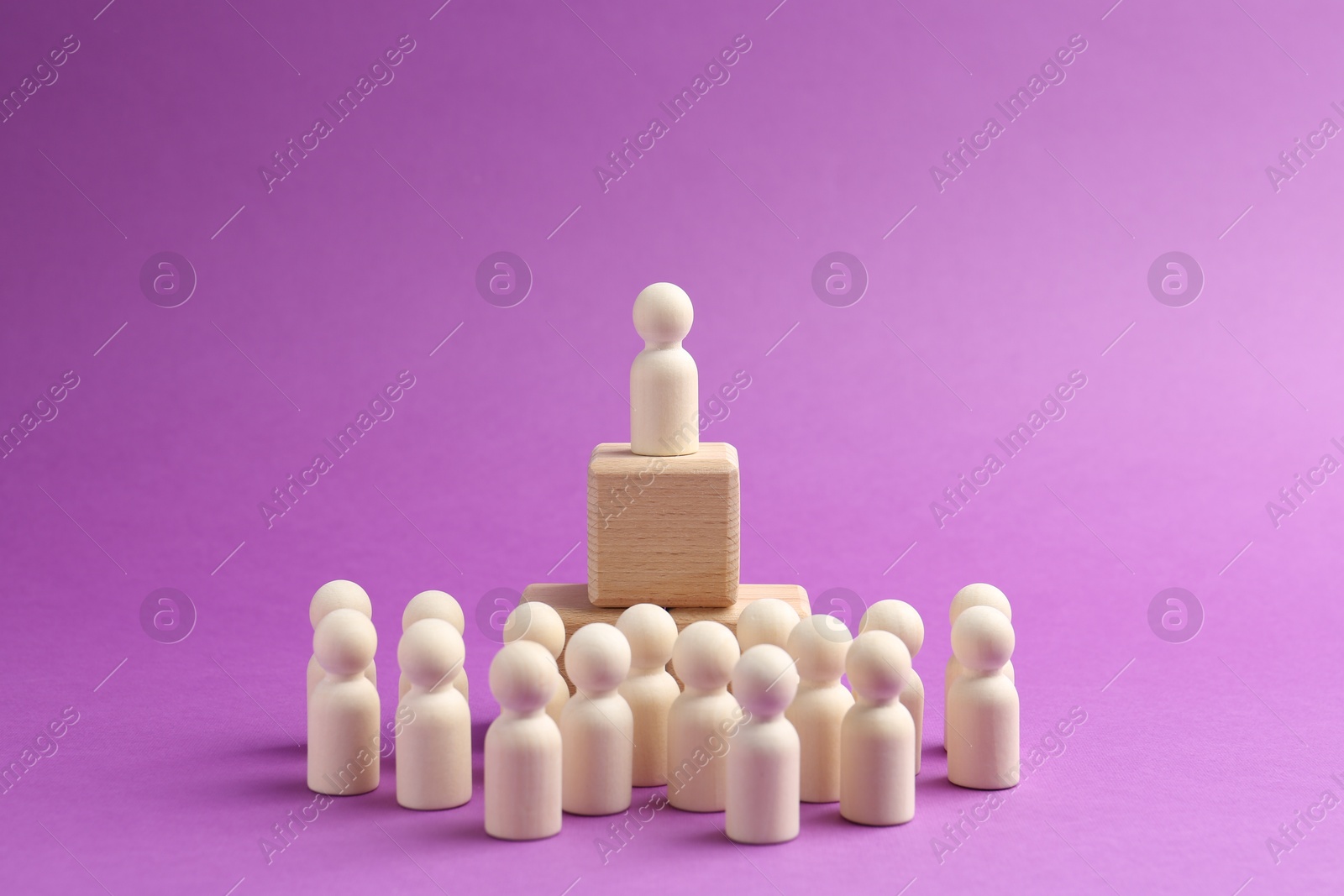 Photo of Human figures near stacked wooden cubes with one figure against violet background. Competition concept