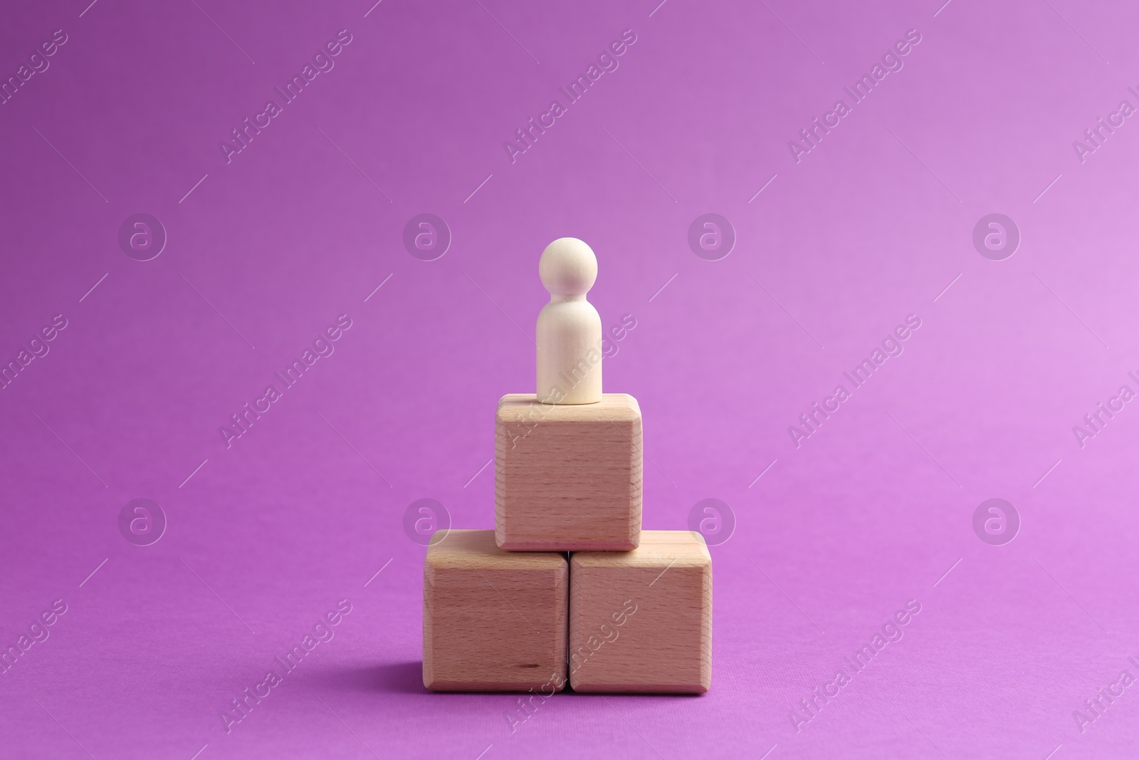 Photo of Human figure on wooden cubes against violet background. Competition concept