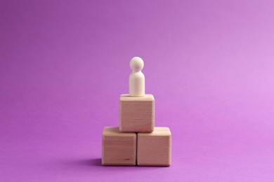 Photo of Human figure on wooden cubes against violet background. Competition concept