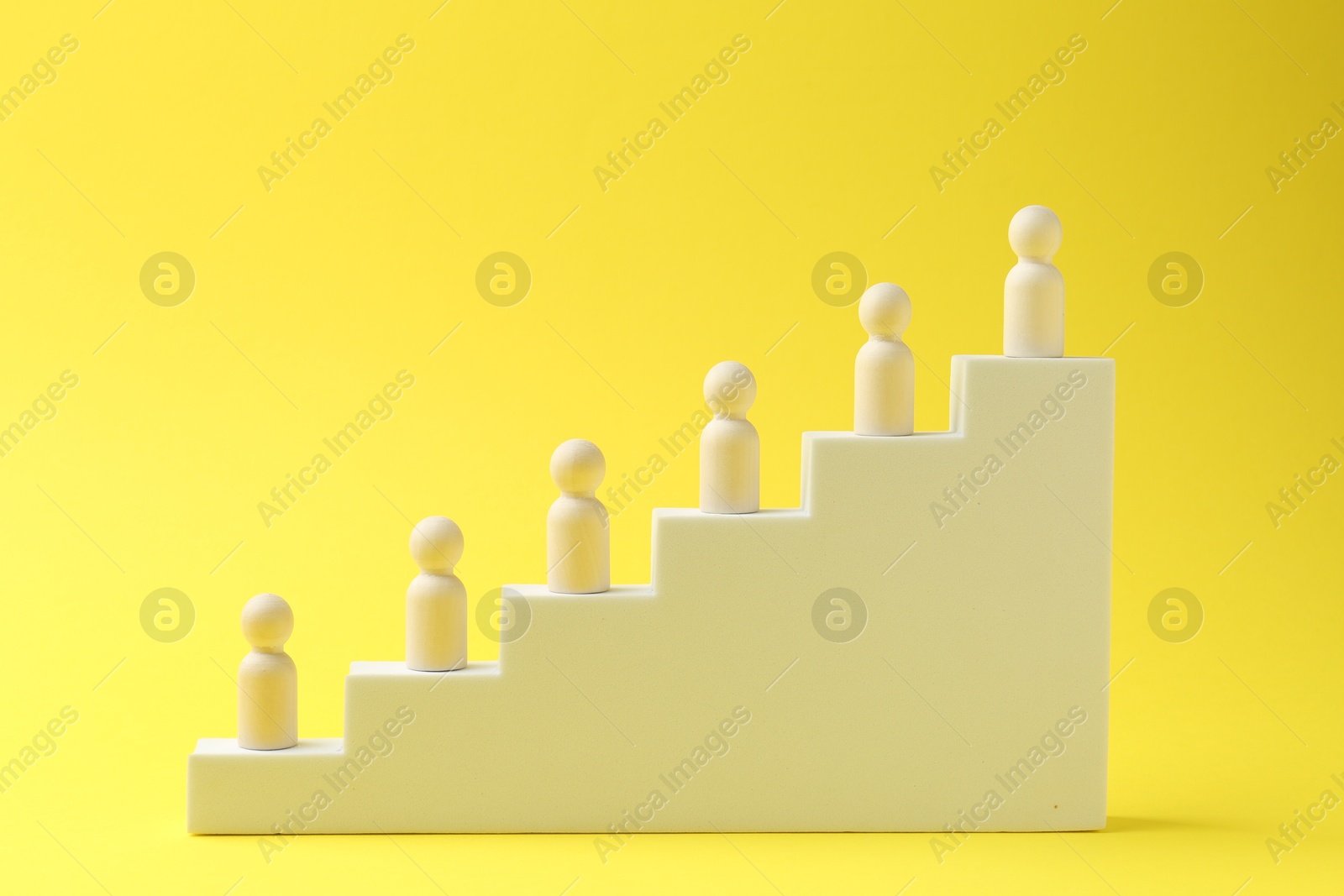 Photo of Human figures on stairs against yellow background. Competition concept