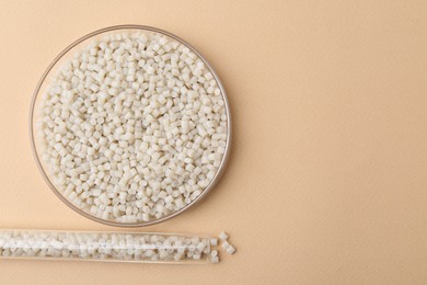 Plastic granules in petri dish and test tube on beige background, flat lay. Space for text