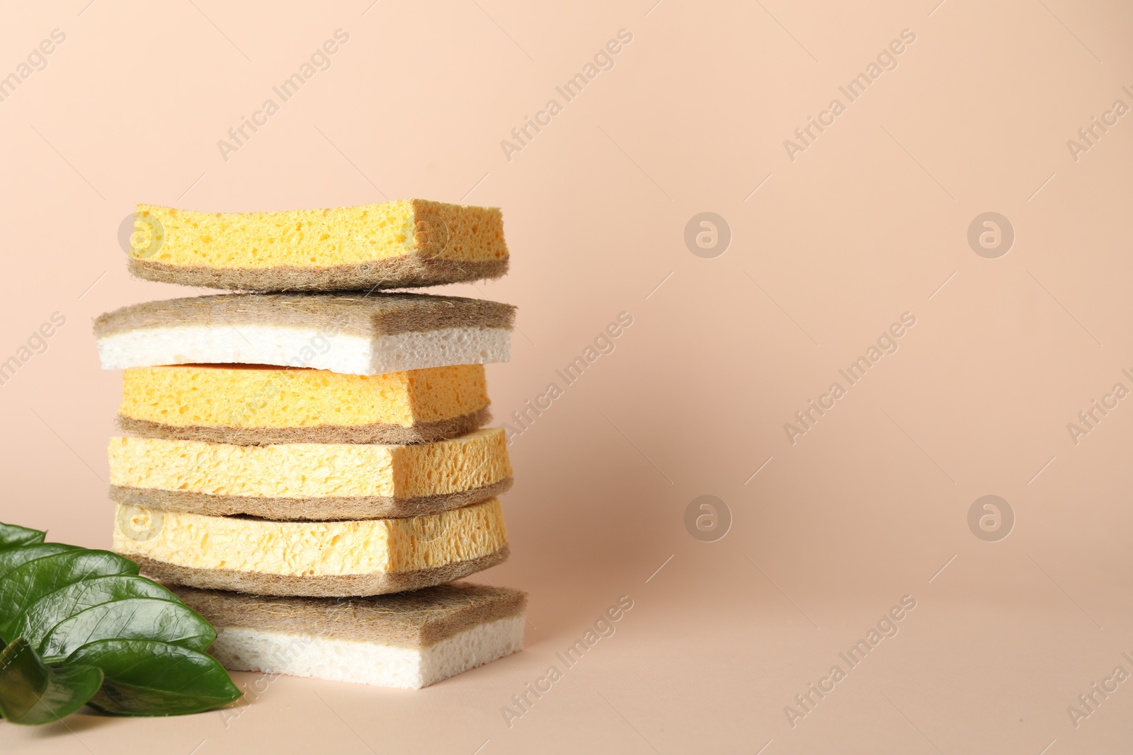 Photo of Stack of different sponges on beige background, closeup. Space for text