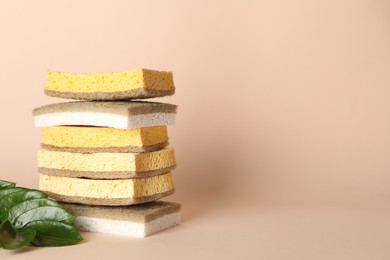 Photo of Stack of different sponges on beige background, closeup. Space for text