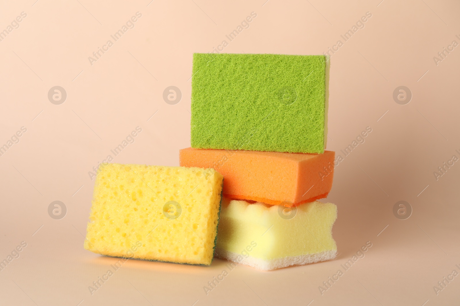 Photo of Different colorful sponges on beige background, closeup