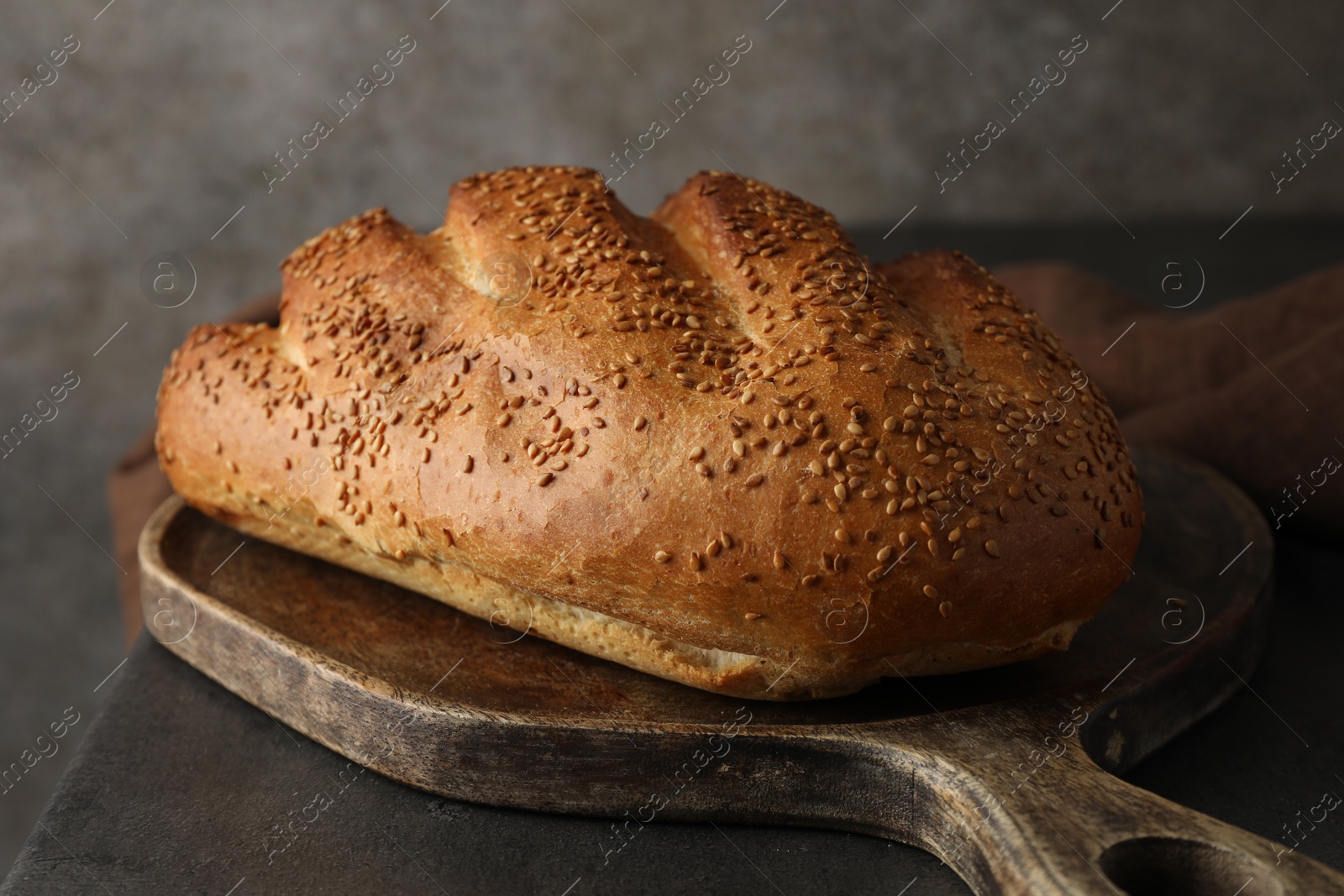 Photo of Freshly baked bread with seeds on grey table, closeup