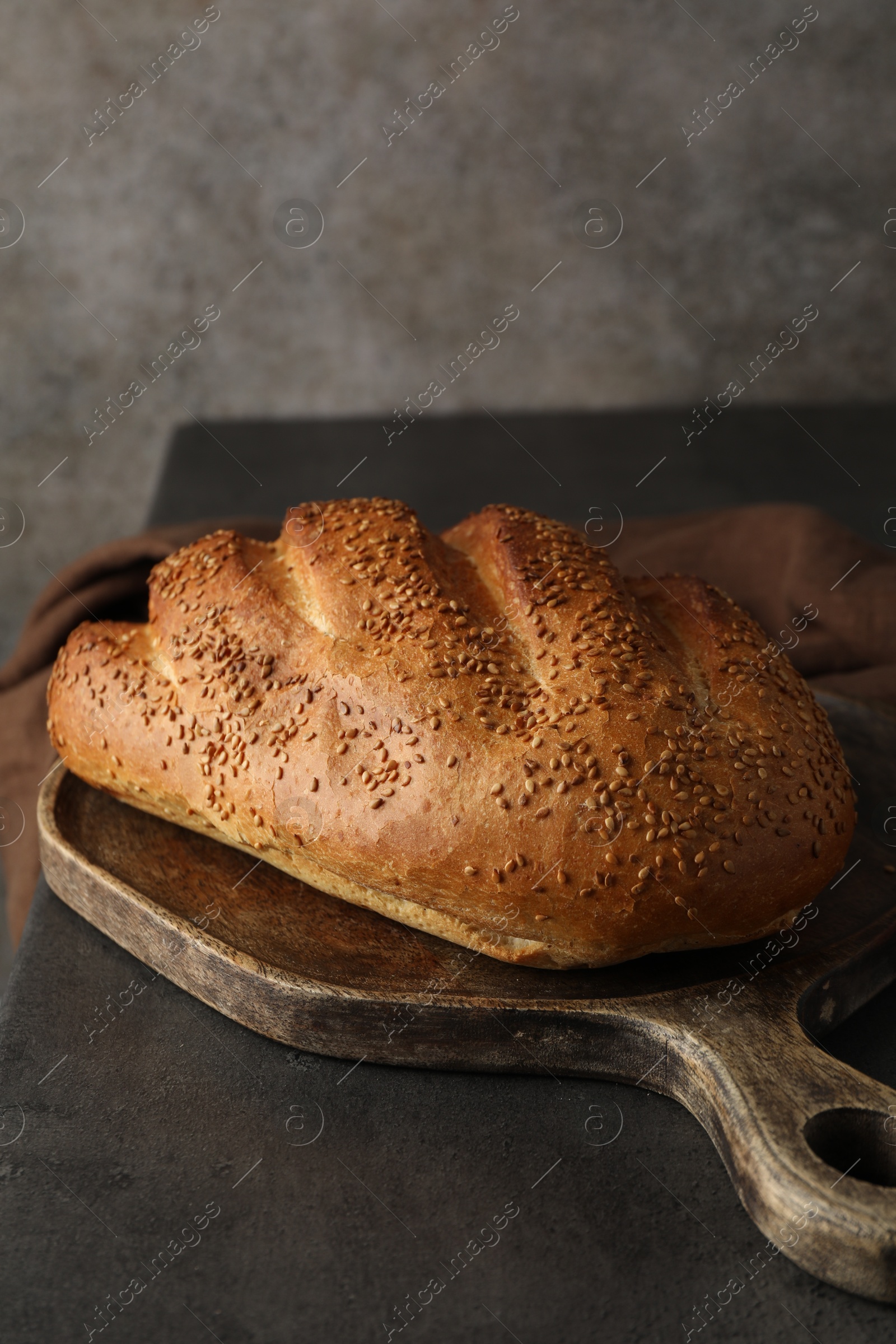 Photo of Freshly baked bread with seeds on grey table, closeup