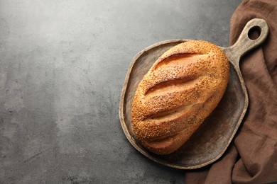 Photo of Freshly baked bread with seeds on grey table, top view. Space for text