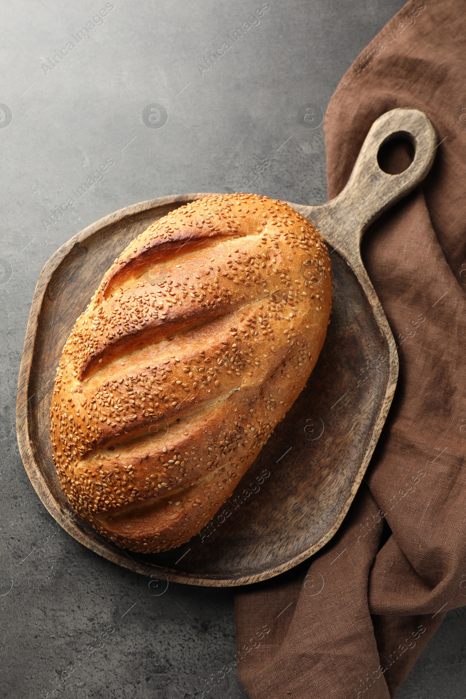 Photo of Freshly baked bread with seeds on grey table, top view