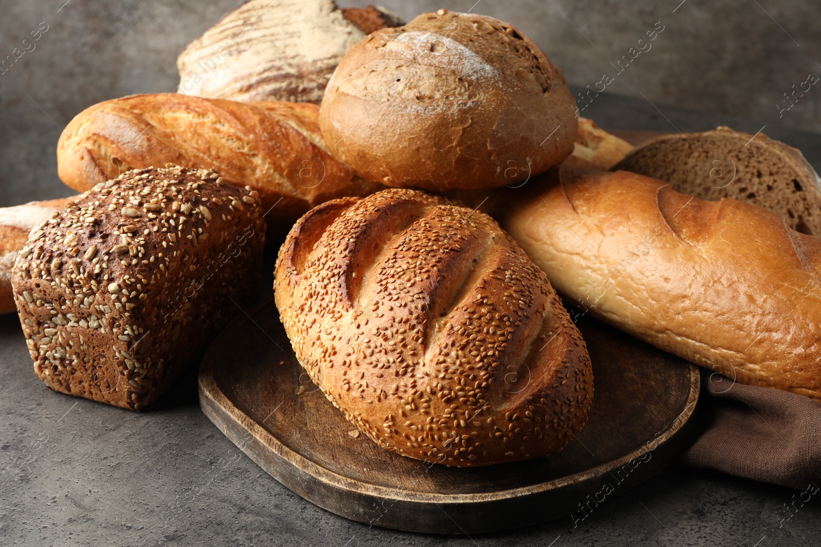 Photo of Different freshly baked bread loafs on grey table, closeup