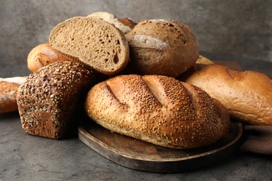 Photo of Different freshly baked bread loafs on grey table, closeup