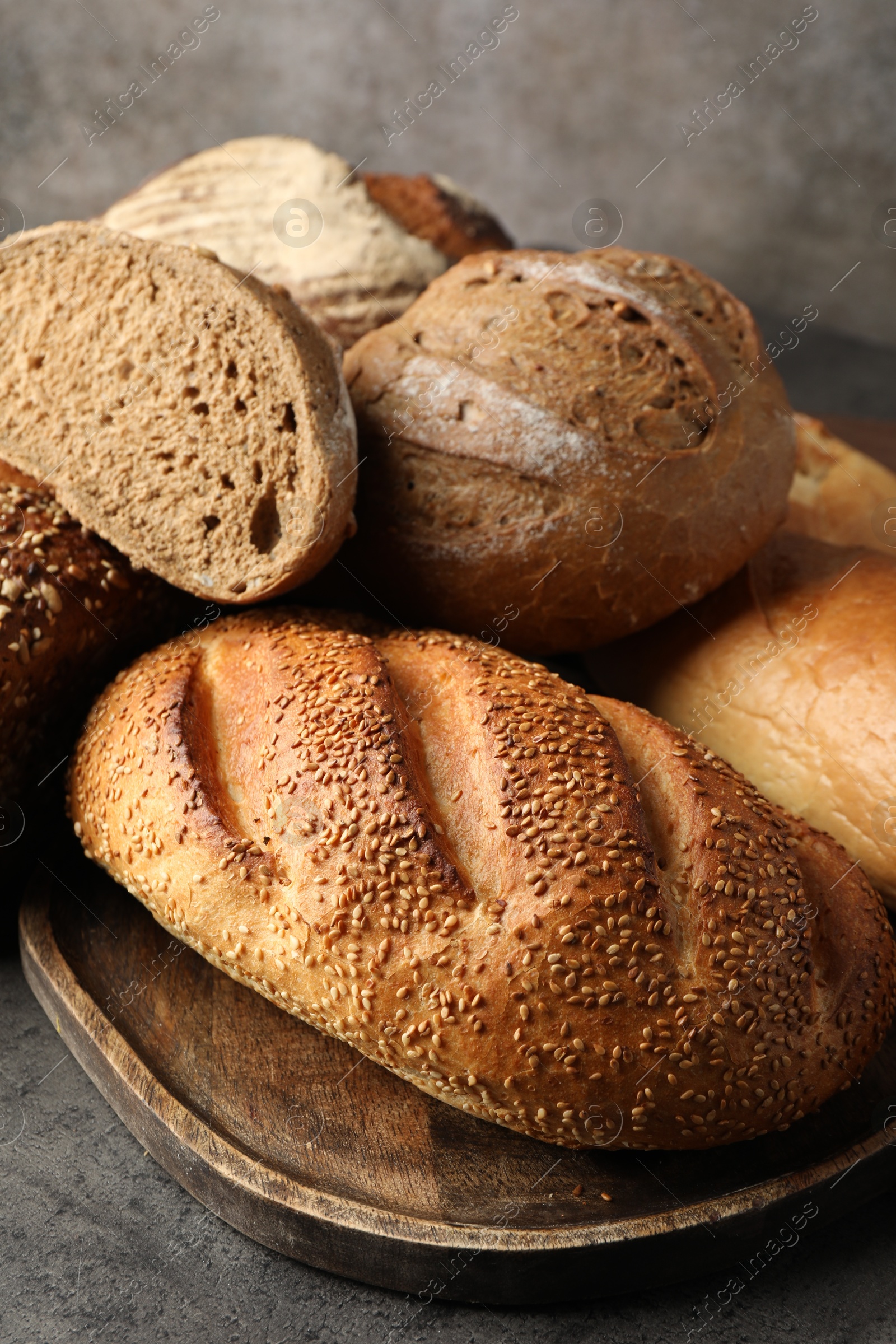 Photo of Different freshly baked bread loafs on grey table, closeup