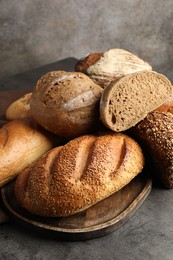 Photo of Different freshly baked bread loafs on grey table