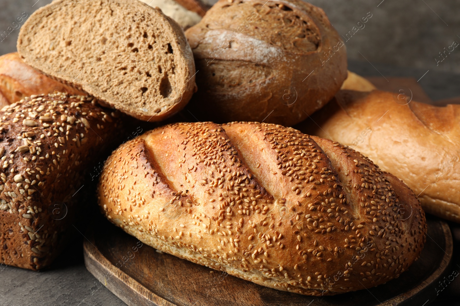 Photo of Different freshly baked bread loafs on grey table, closeup