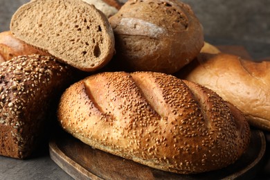 Photo of Different freshly baked bread loafs on grey table, closeup