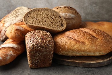 Photo of Different freshly baked bread loafs on grey table, closeup