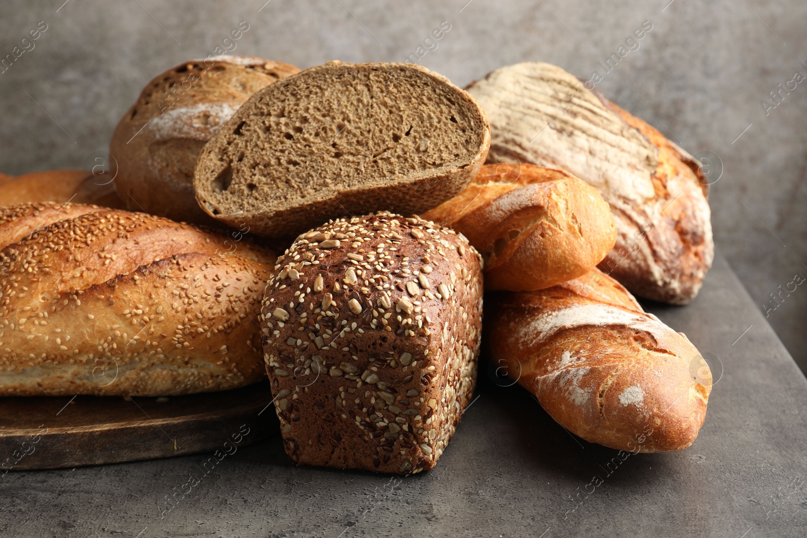 Photo of Different freshly baked bread loafs on grey table, closeup