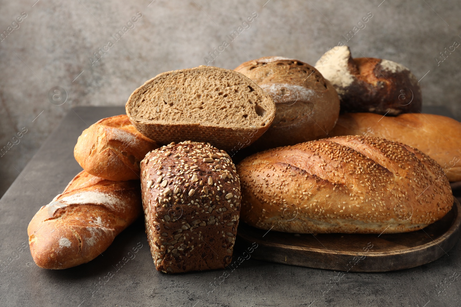 Photo of Different freshly baked bread loafs on grey table