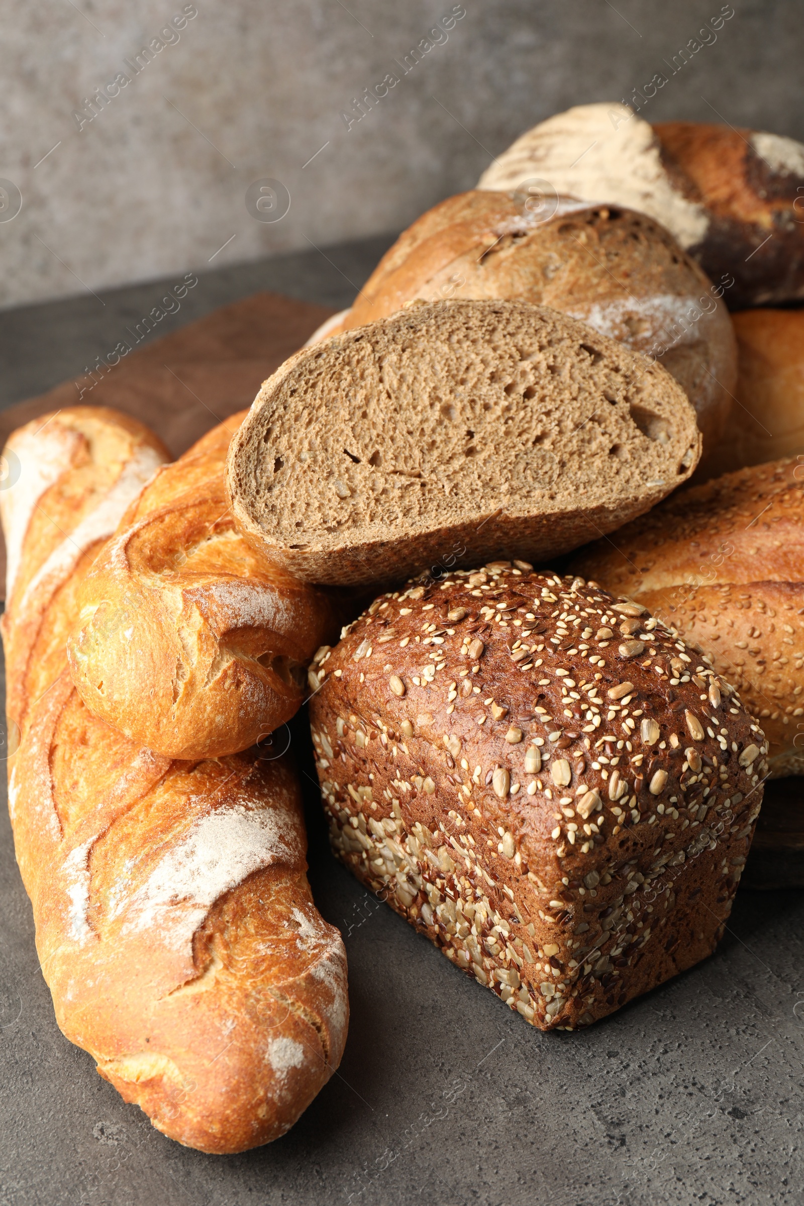 Photo of Different freshly baked bread loafs on grey table, closeup