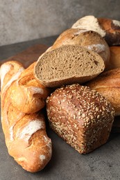 Photo of Different freshly baked bread loafs on grey table, closeup