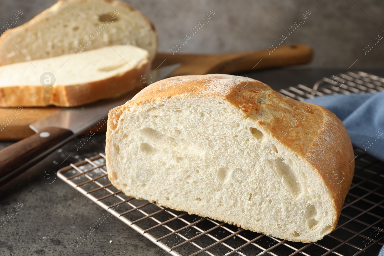 Photo of Cut fresh bread and knife on grey table, closeup