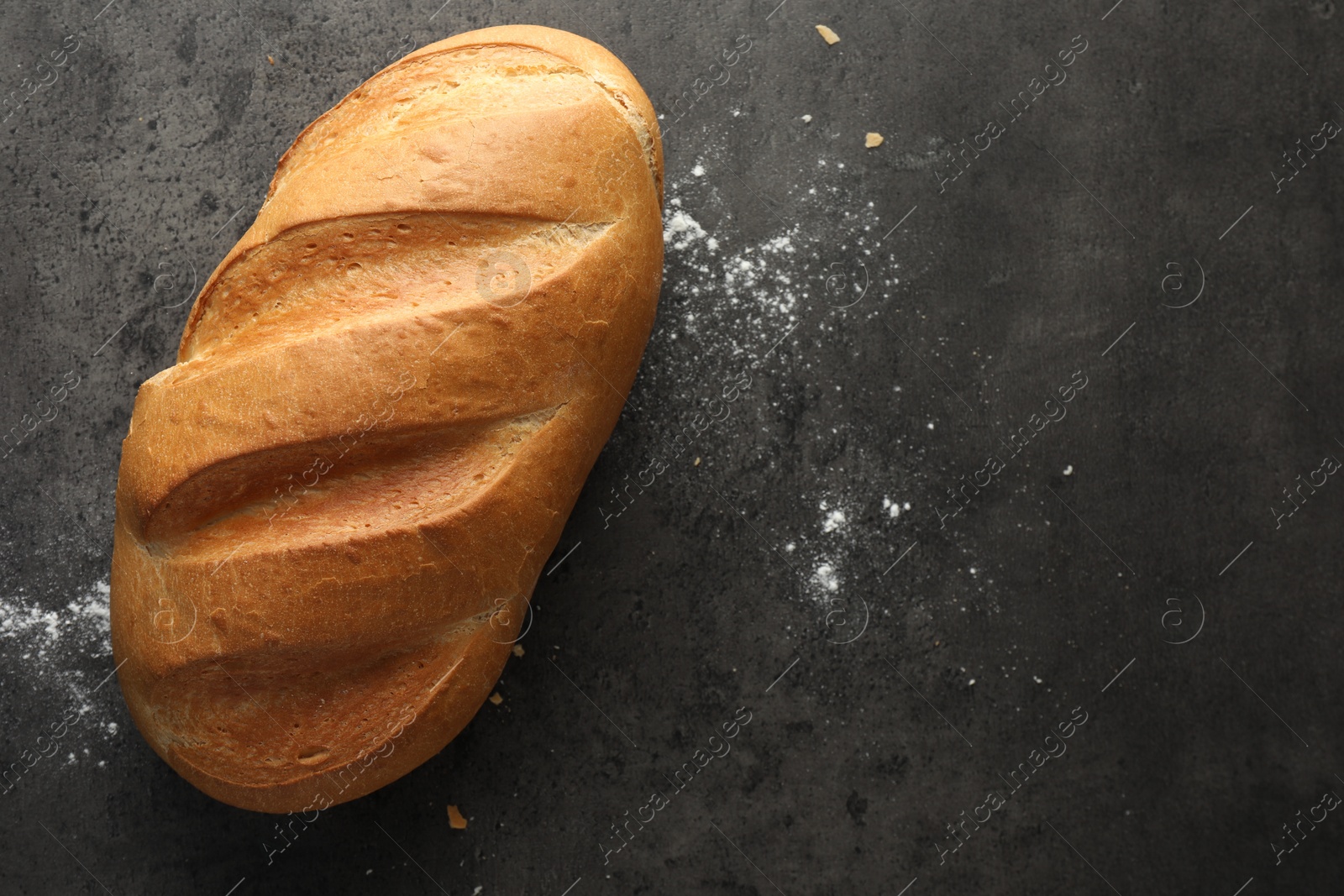 Photo of Freshly baked bread on grey table, top view. Space for text