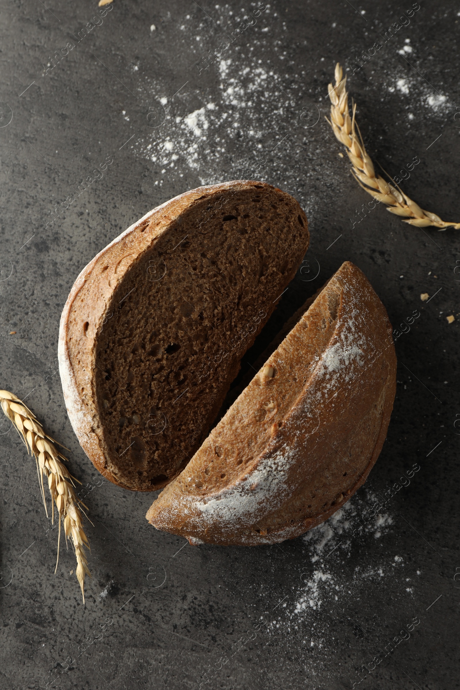 Photo of Halves of fresh bread and spikes on grey table, flat lay