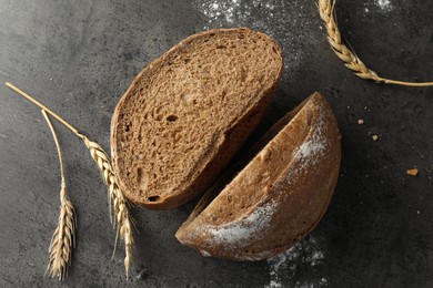 Photo of Halves of fresh bread and spikes on grey table, flat lay