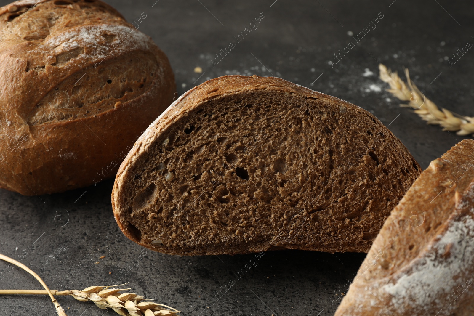 Photo of Freshly baked bread and spikes on grey table, closeup