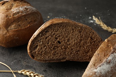 Photo of Freshly baked bread and spikes on grey table, closeup