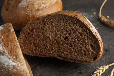 Photo of Freshly baked bread and spikes on grey table, closeup